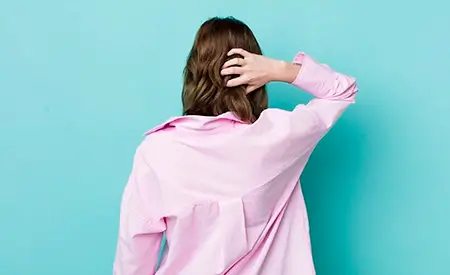 imagem com uma mulher de camisa social rosa, de costas, em sinal de timidez, em um fundo azul